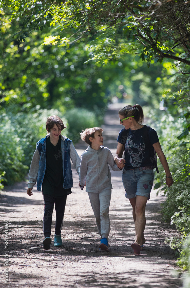 Mother and sons walking on sunny park path Mother and sons walking on sunny park path