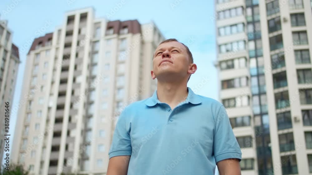 Portrait of a young confident man on the background of apartment buildings, camera tracking Portrait of a young confident man on the background of apartment buildings, camera tracking