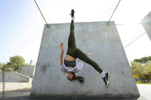 Fotografie Girl jumps upside down on a parkour playground