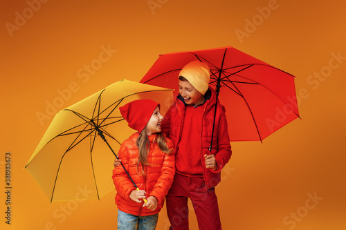 Happy emotional children in autumn clothes, smiling standing under umbrellas.
