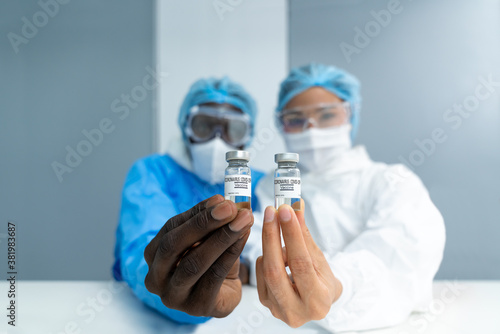 Close up on Vaccine. Multiethnic scientists in laboratory holding vial of coronavirus vaccine. The success of Virologists who invented the vaccine for Covid-19. Part of 2019-2020 global pandemic.