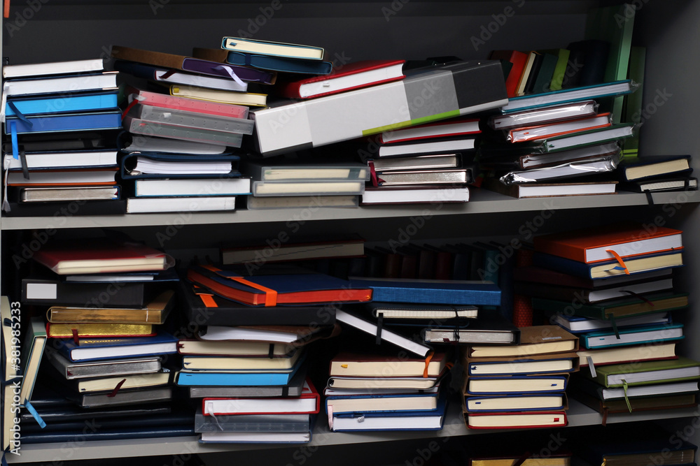 Stack of various leather-bound diaries or books in a gray bookcase Stack of various leather-bound diaries or books in a gray bookcase