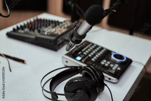 Working place of radio host. Close up of headphones, microphone and sound mixing desk on the table in recording studio or broadcast room