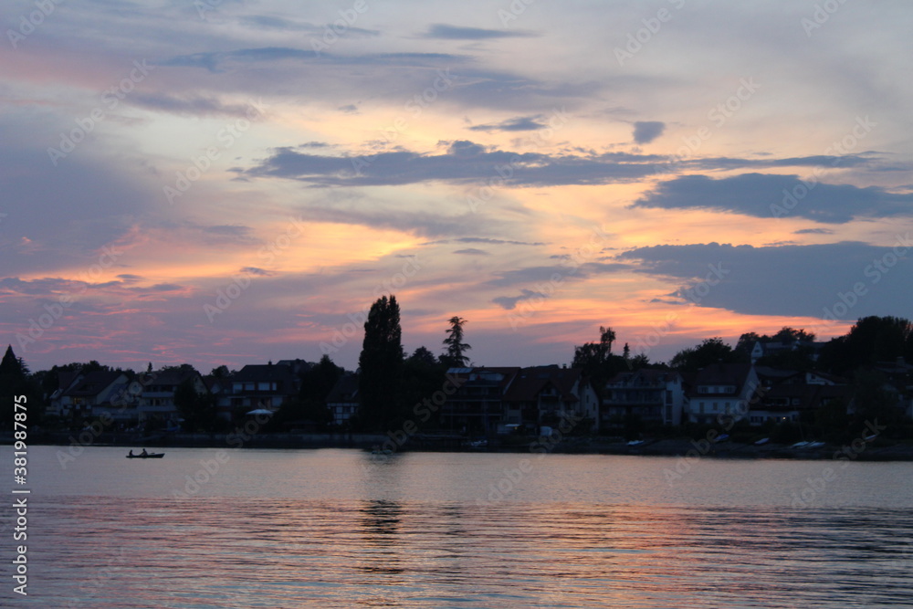 A beautiful sunset on Lake Constance on the water is a rowboat.
