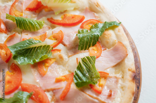 Italian pizza with ham, tomatoes and salad close-up. Cooking concept in the style of Italian cuisine.