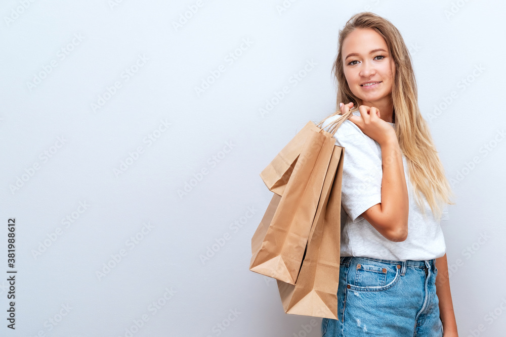 Young female in casual cloth with paper shopper bags on grey backdrop. Shopping. Black friday and cyber monday sales. Zero waste Young female in casual cloth with paper shopper bags on grey backdrop. Shopping. Black friday and cyber monday sales. Zero waste
