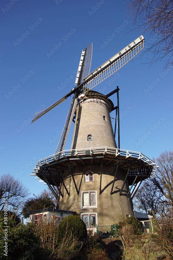 High brick windmill on a defensive wall and canal of the Dutch city Alkmaar for grinding corn. Called the Molen van Piet. Netherlands, December