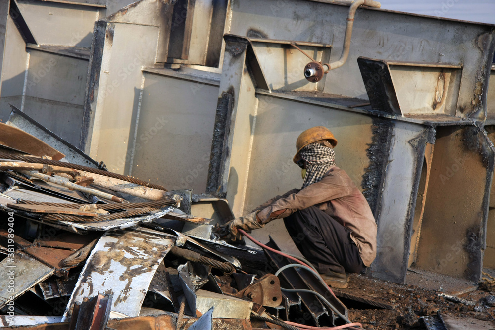 Fototapeta premium Shipbreaking Yard in Darukhana, Mumbai, India – INS Vikrant dismantling with scrap metal & workers in background