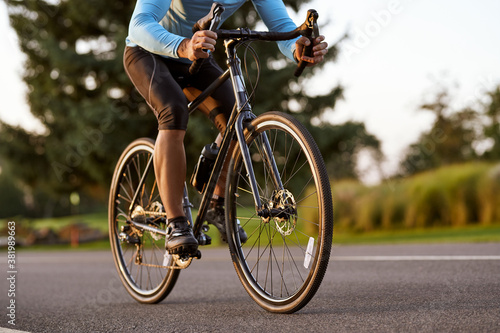 Cropped shot of a road bicycle racer in sportswear cycling in park on a summer day