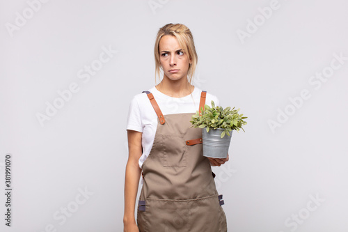 young woman gardener feeling sad, upset or angry and looking to the side with a negative attitude, frowning in disagreement