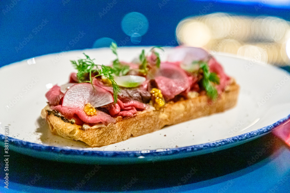 Bruschetta with roast beef, radishes and vegetables on a plate