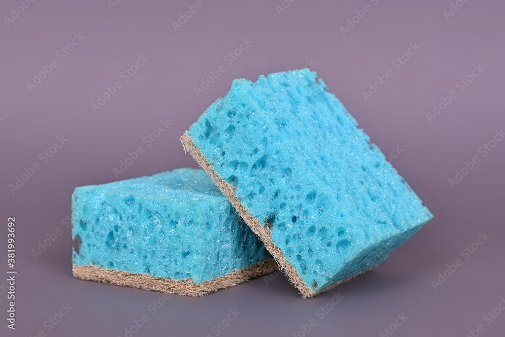 A porous blue washcloth for cleaning the apartment and washing dishes on a gray background.