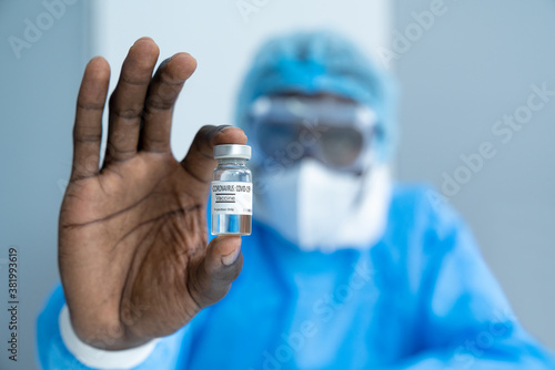 Close up on Vaccine. African American scientist in laboratory holding vial of coronavirus vaccine. The success of Virologists who invented the vaccine for Covid-19. Part of 2019-2020 global pandemic.