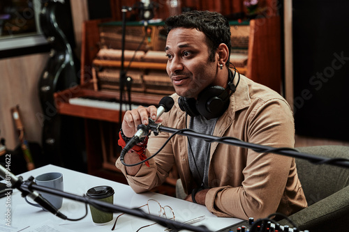 Photography Portrait of young male radio host looking focused while speaking in microphone,