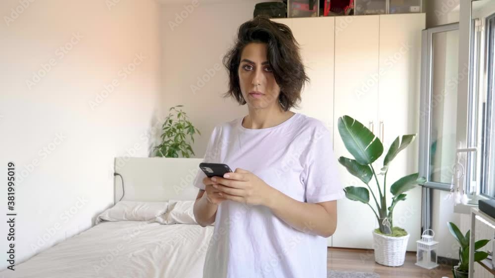 Portrait of woman holding smart phone in bedroom