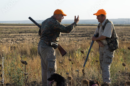 Fototapet Duck hunters with shotgun walking through a meadow.