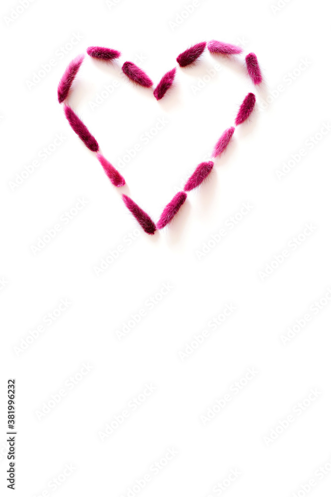 Heart laid out of purple dried flowers isolated on a white background. Happy valentine's day greeting card design. Top view