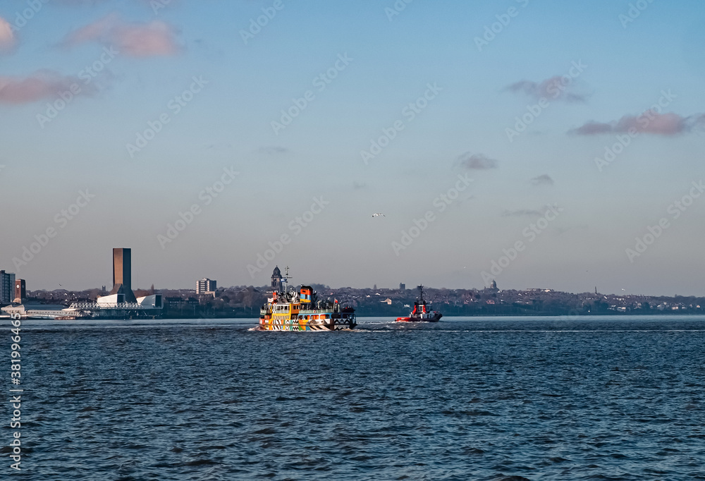 Liverpool, UK. Beautiful colorful long exposure shot of river Mersey from Albert Dock with smooth reflections of night lights from the other side of a shore and a boat. 