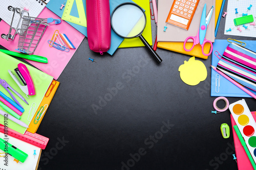 Different school supplies on blackboard background