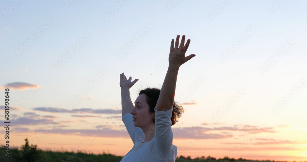 Female practicing qigong in summer fields with beautiful sunset on background Female practicing qigong in summer fields with beautiful sunset on background