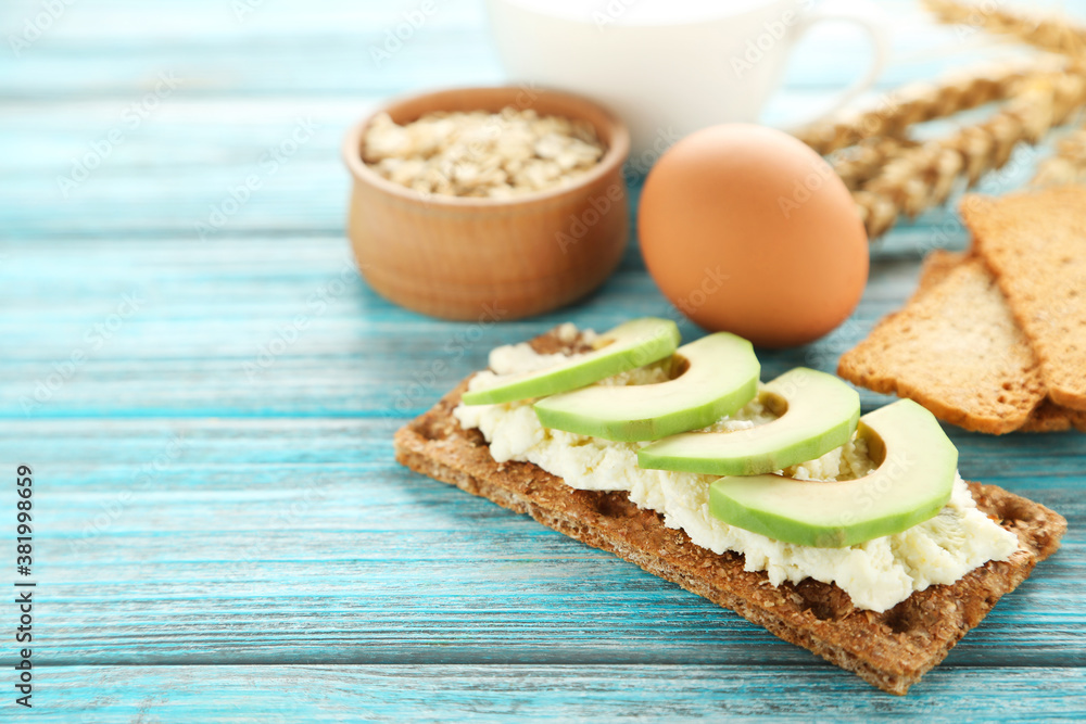 Crispbread with cream cheese, avocado and egg on blue wooden table