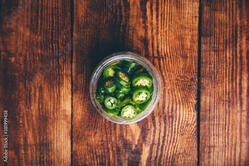 Sliced Jalapeno Peppers in Glass Jars for Canning on Wooden Table. View from Above