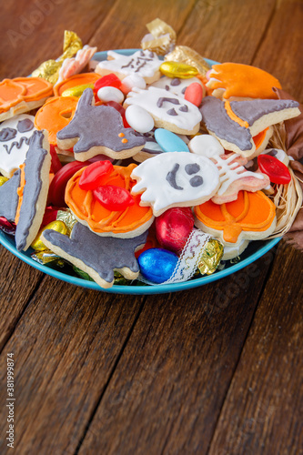 Halloween Jack o Lantern candy bowl with candy and halloween cookies Trick or Treat on black wooden background