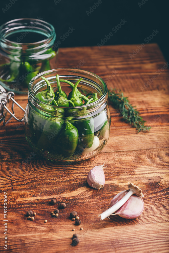 Jalapeno Peppers in a Glass Jar for Pickling with Spices on Wooden Table. Copy Space Jalapeno Peppers in a Glass Jar for Pickling with Spices on Wooden Table. Copy Space