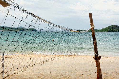 Beach volleyball net on the empty beach with the blue sea and sky. Copy space. 