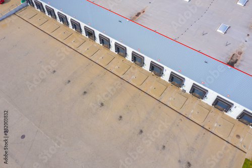 Aerial view of goods warehouse. Logistics center in industrial city zone from above. Aerial view of trucks loading at logistic center