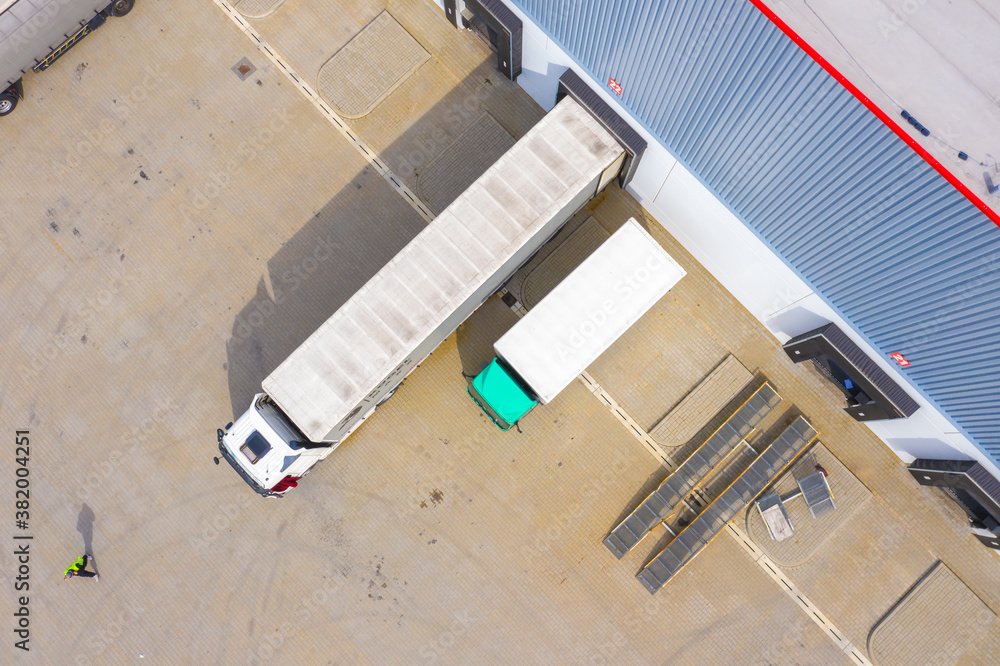 Aerial view of goods warehouse. Logistics center in industrial city zone from above. Aerial view of trucks loading at logistic center. View from drone. Aerial view of goods warehouse. Logistics center in industrial city zone from above. Aerial view of trucks loading at logistic center. View from drone.