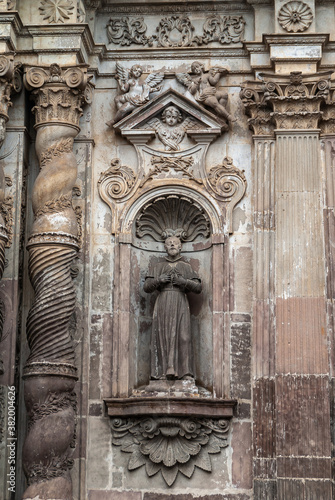Quito, Ecuador - December 2, 2008: Historic downtown. Closeup of statue of male saint on Brown stone entrance facade to La Compania Church of the Jesuits. © Klodien