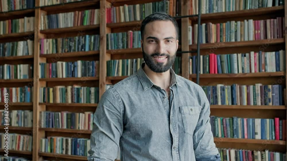 Young Guy On The Background Of Shelves With Books In The Library. Young Guy On The Background Of Shelves With Books In The Library.