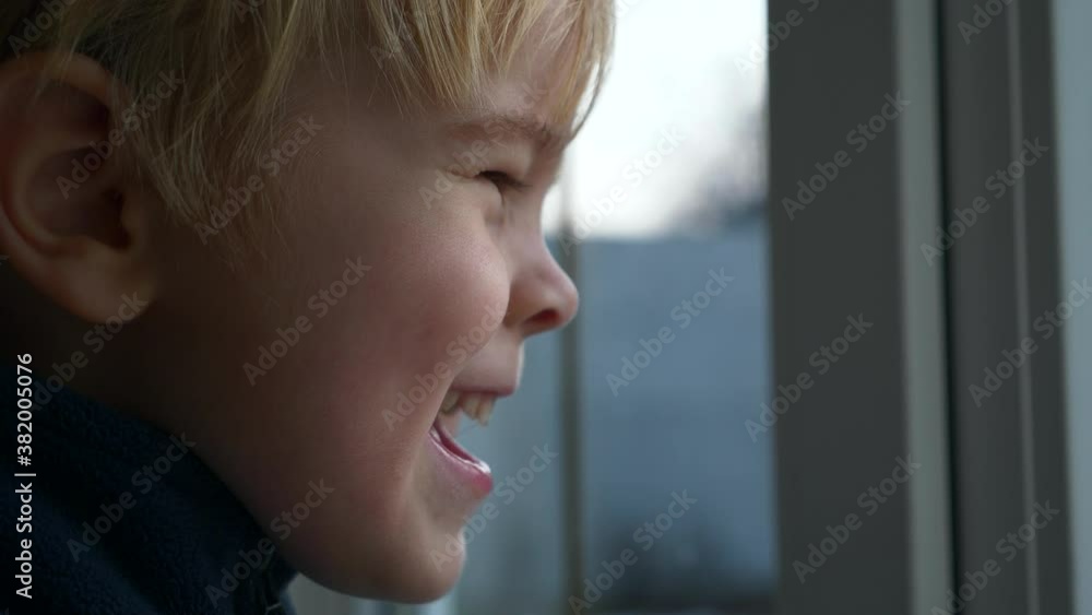 Thoughtful Child Start Smiling Laughing while Watching at Window. Serious Boy Stands Watching Looking at Backyard Outdoor. Autumn Winter Spring. 2x Slow motion 60 fps 4K