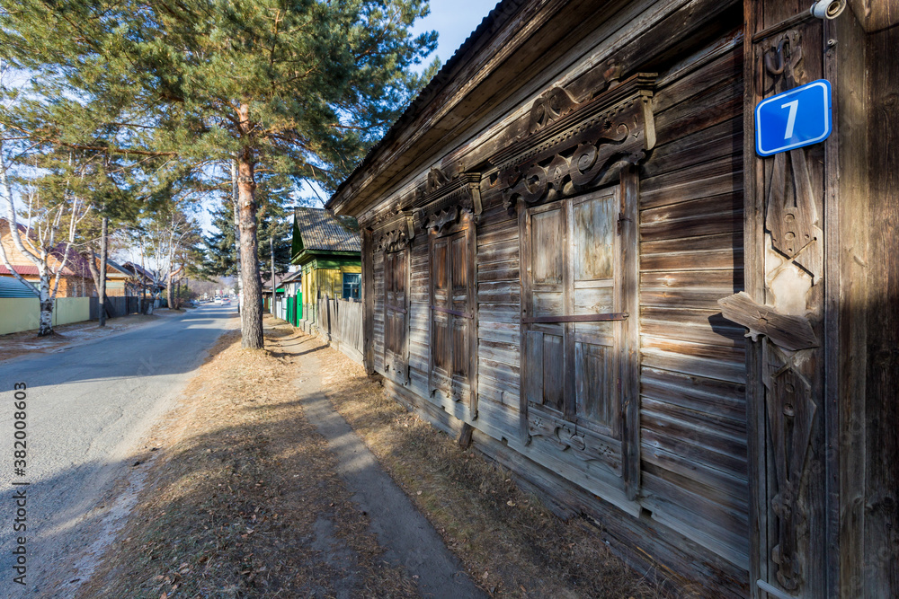 An old one-story wooden house with carved shutters in the Russian style. Wooden house on the street of a Russian town