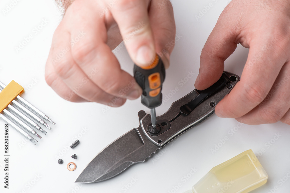 Technician joints the parts of a folding knife together with a screwdriver Technician joints the parts of a folding knife together with a screwdriver