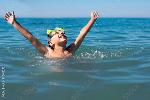 A boy with scuba diving glasses in the sea enjoys the summer sun, vacation and fun swimming