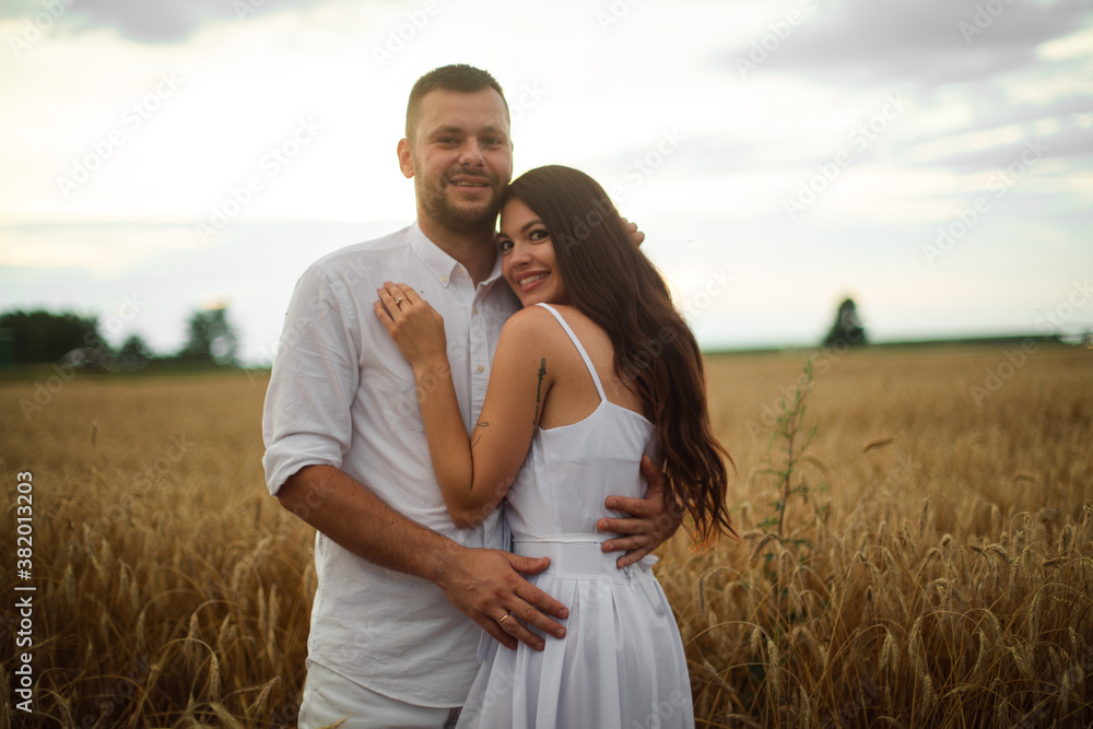 Full length stock photo of a romantic couple in white clothes hugging in the wheat field at sunset. Full length stock photo of a romantic couple in white clothes hugging in the wheat field at sunset.