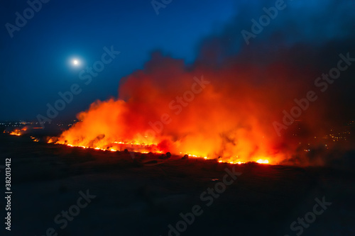 Forest fire, aerial view at night. Large burning area engulfed in fire and smoke, dry season, climate change concept.