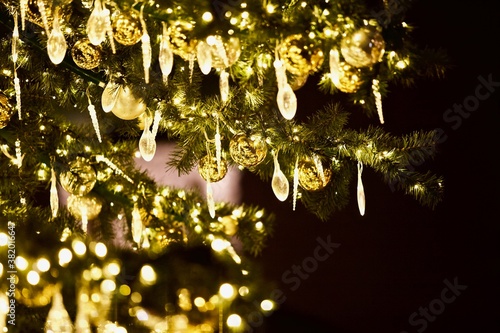 Bright green Christmas tree branches decorated with beautiful colorful Christmas decorations, bright toys, sparkling garlands and balls. Festive Christmas lights and Magic decorations close-up.