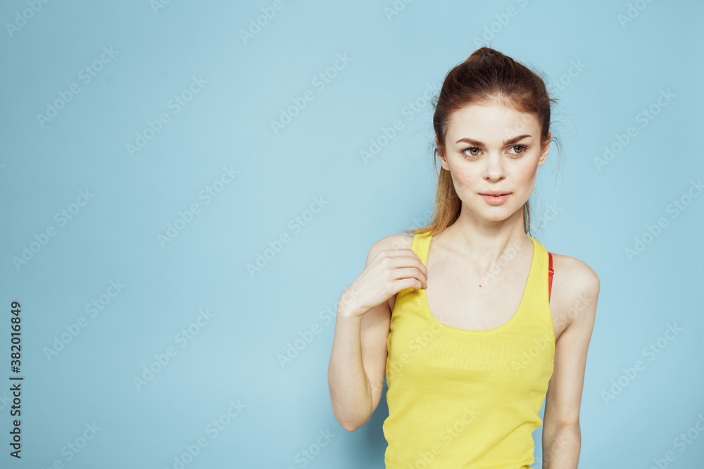 Sportive woman yellow tank top pigtail towards fitness blue background Sportive woman yellow tank top pigtail towards fitness blue background