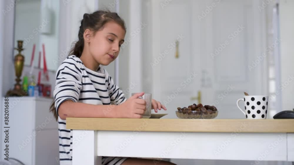 Happy child little girl eat date fruit in the summer home kitchen. Happy child little girl eat date fruit in the summer home kitchen.