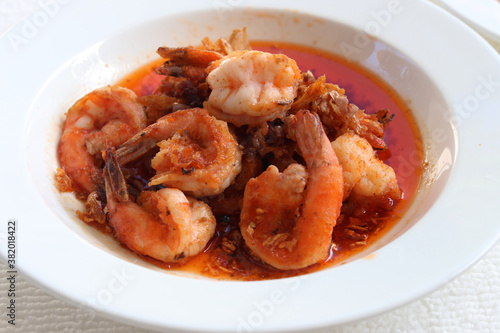 Thai style deep fried prawns with garlic, sweet and sour sauce in white plate.
