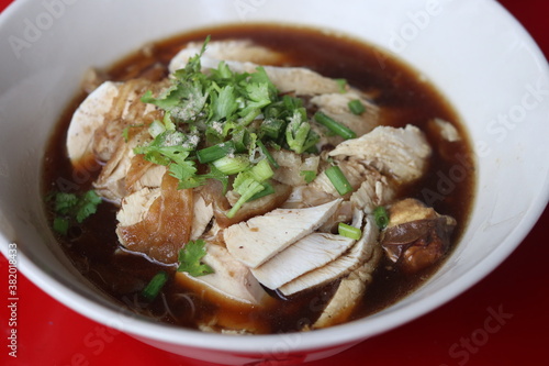 Thai style of chicken noodle with bitter gourd in white bowl on red table background. One of the most popular Thai street food dishes to try.