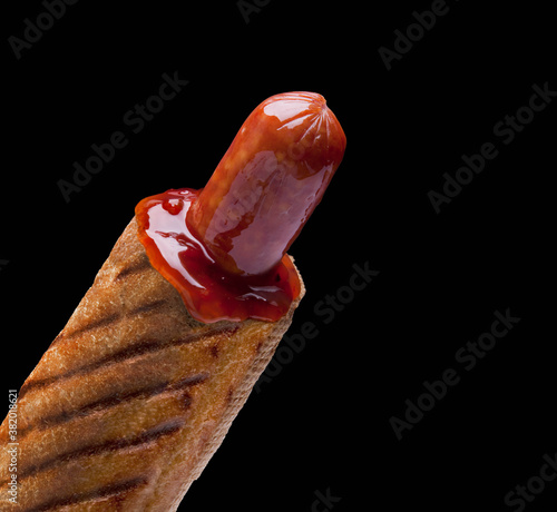 A delicious french hot dog with sauce on a black background