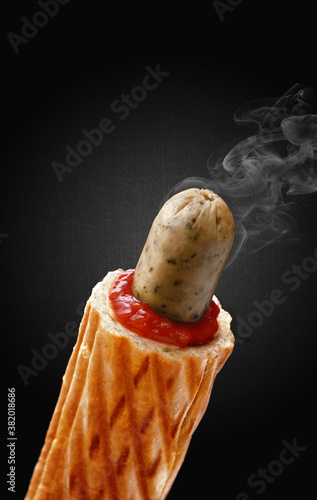 A delicious french hot dog with while bavarian sausage on a black background