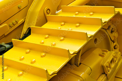 Bulldozer tracks and drive gear with sprocket mechanism, large construction machine with bolts and yellow paint coating, heavy industry, detail