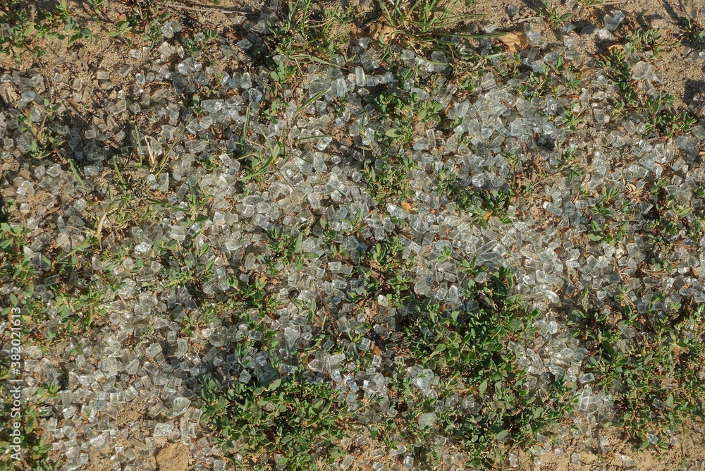 texture of pieces of white broken glass on brown ground and in green grass texture of pieces of white broken glass on brown ground and in green grass