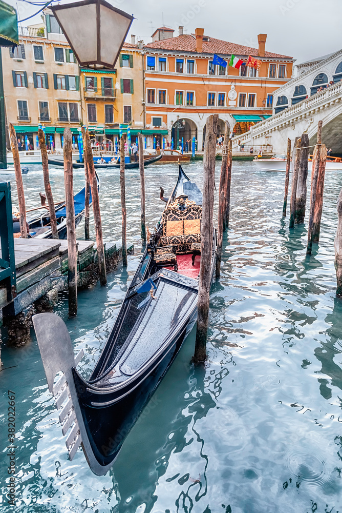 Traditional gondola docked next to Rialto Bridge in Venice, Italy