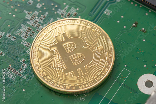 Gold Bitcoin on green chipset. Close-up, macro shot.